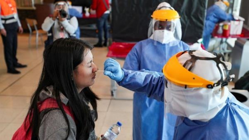 Personal médico realiza pruebas PCR en un aeropuerto