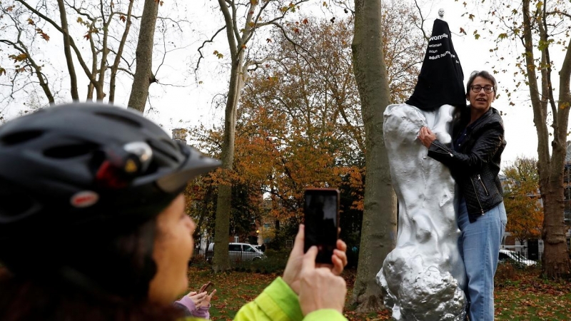 Una mujer toma una foto mientras una activista cubre con una camiseta la figura desnuda de la estatua en homenaje a Mary Wollstonecraft, en Newington Green, Londres. REUTERS/Paul Childs