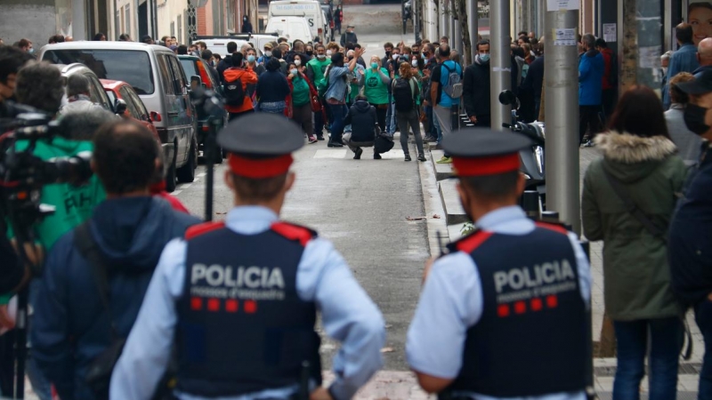 3.	Dos agents dels Mossos d’Esquadra, d’esquena, miren cap als membres de la PAH concentrats per evitar un desnonament previst al carrer Borràs, a Nou Barris, el 4 de noviembre de 2020.