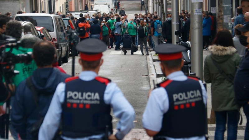 3.	Dos agents dels Mossos d’Esquadra, d’esquena, miren cap als membres de la PAH concentrats per evitar un desnonament previst al carrer Borràs, a Nou Barris, el 4 de noviembre de 2020.