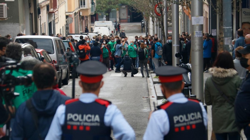 3.	Dos agents dels Mossos d’Esquadra, d’esquena, miren cap als membres de la PAH concentrats per evitar un desnonament previst al carrer Borràs, a Nou Barris, el 4 de noviembre de 2020.