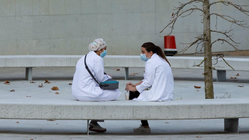 Dos sanitarias conversan en un banco en las inmediaciones del hospital Vall d'Hebron de Barcelona