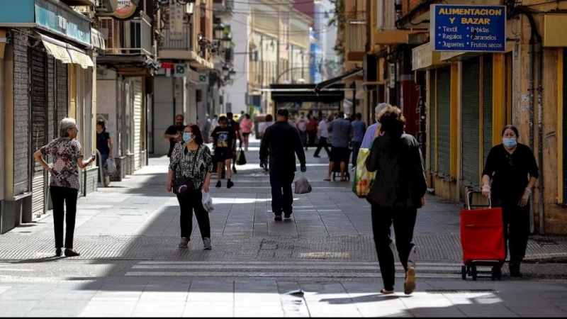 Diverses persones passejant per un carrer de València.