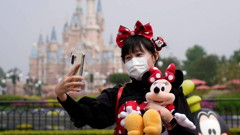 Una visitante se hace una foto frente al castillo de Disneyland Shanghai. Los parques temáticos han visto caer drásticamente las visitas por la covi-19.