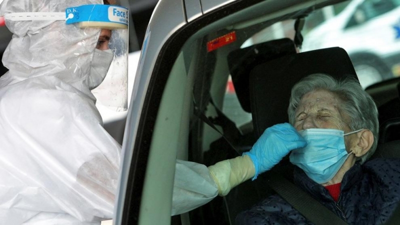 Una sanitaria protegida con EPI toma una muestra para una prueba PCR frente al hospital de Gandía.