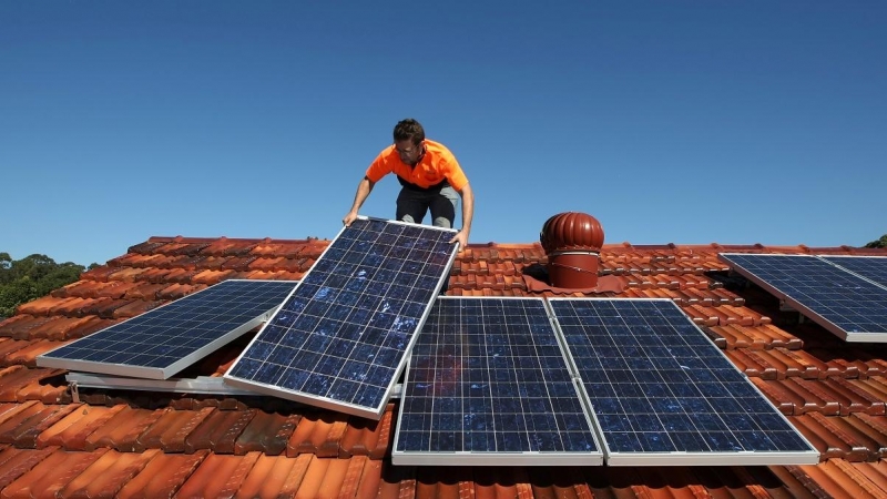 Un operario trabaja colocando paneles solares en un tejado de una vivienda.