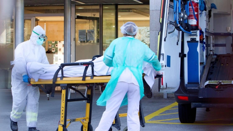 Dos sanitarios trasladan a un paciente de covid-19 en una camilla a un hospital.