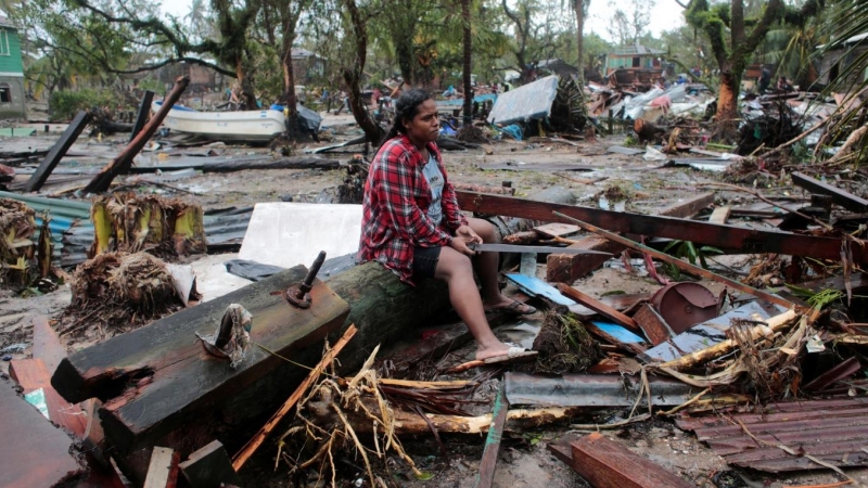 Una mujer está sentada en un poste de luz derribado mientras contempla su casa destruida tras el paso del huracán Iota, en Puerto Cabezas, Nicaragua.