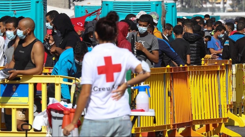 Una voluntaria de Cruz Roja junto a varios inmigrantes este jueves en el muelle de Arguineguín.