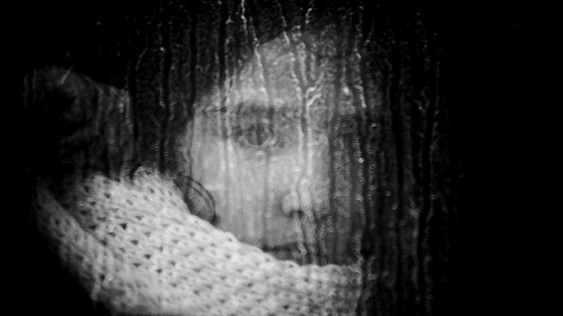 Una niña mira a través del cristal de un autobús camino al campamento de Moria.