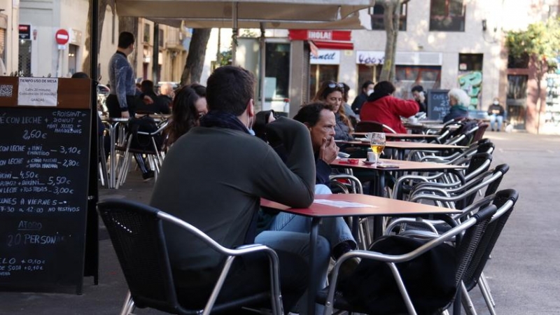 Una cambrera netejant una taula d'una terrassa del bar Las Euras a la plaça de la Vila de Gràcia de Barcelona.