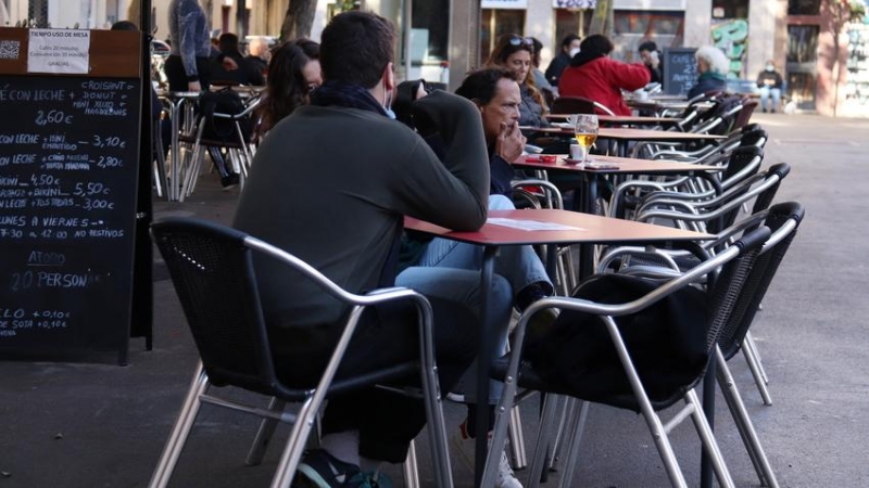 Una cambrera netejant una taula d'una terrassa del bar Las Euras a la plaça de la Vila de Gràcia de Barcelona.