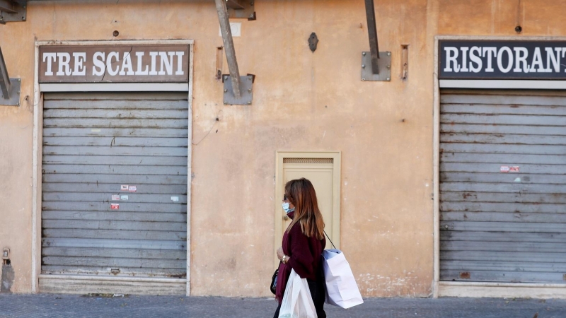 Una mujer pasea frente a un restaurante cerrado en Roma, Italia