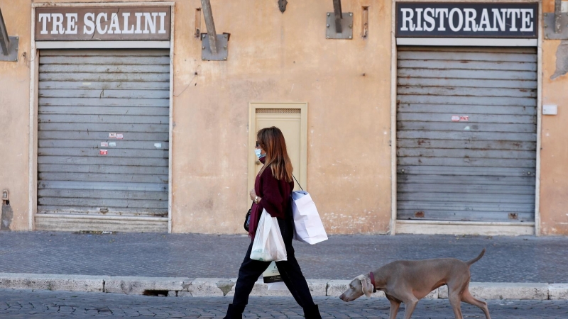 Una mujer pasea frente a un restaurante cerrado en Roma, Italia