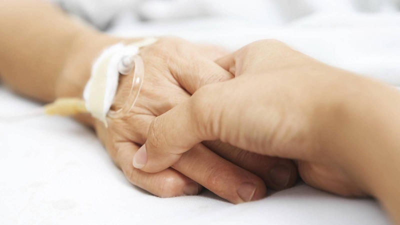 Una persona coge la mano a un paciente.