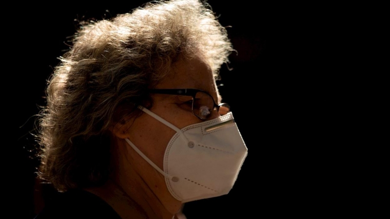 Una mujer camina por una calle de Barcelona con mascarilla.