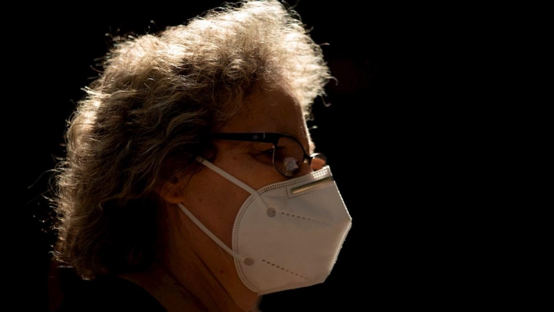 Una mujer camina por una calle de Barcelona con mascarilla.