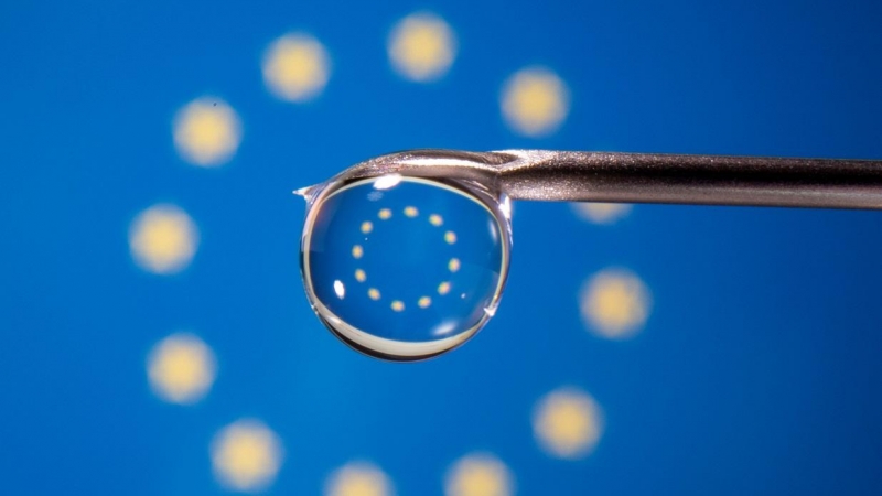 La bandera de la UE se refleja en la gota de una jeringuilla.