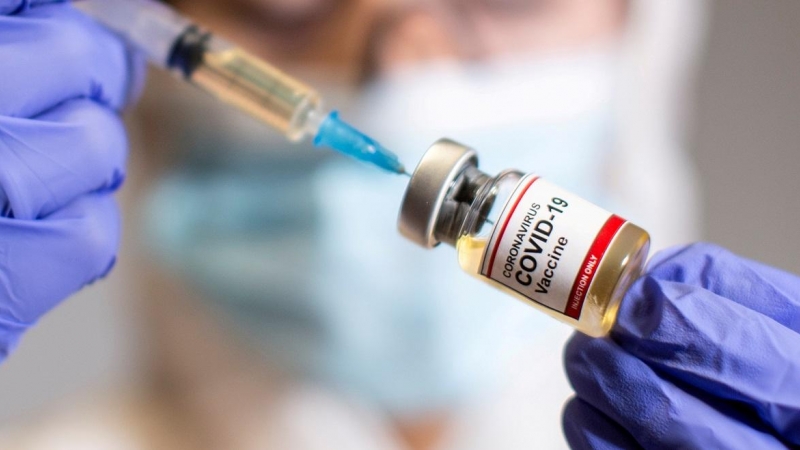 Una sanitaria sostiene una muestra donde se lee 'Vacuna covid-19'