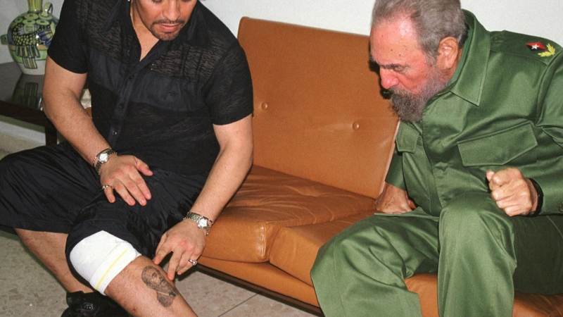 La leyenda del fútbol argentino Diego Maradona, entonces en Cuba en rehabilitación por abuso de cocaína, muestra al presidente cubano Fidel Castro un tatuaje de él en su pierna, dentro del Palacio de la Revolución en La Habana, en esta foto de archivo del