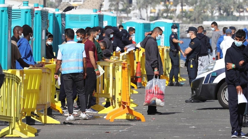 Varios inmigrantes llegados la pasada madrugada esperan este miércoles en el muelle de Arguineguín (Gran Canaria) a que les tomen las huellas dactilares y la filiación.