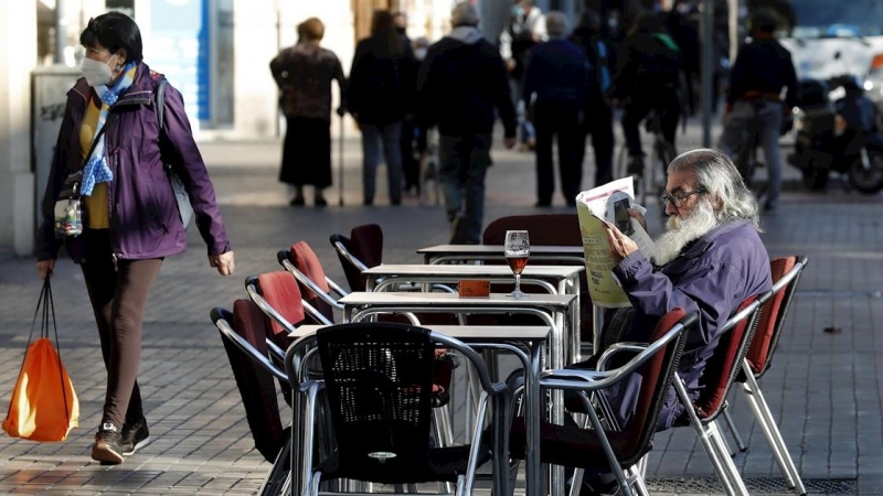 23/11/2020  - Un hombre lee un periódico en la terraza de un bar de Barcelona.