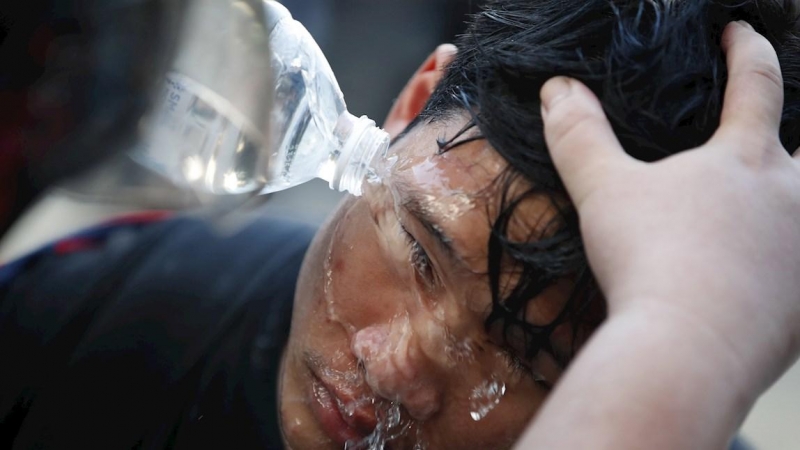 Activistas pro-democráticos ayudan a un compañero herido por una granada lacrimógena lanzada por la Policía durante una manifestación convocada durante el debate sobre la reforma de la Constitución en Bangkok (Tailandia).