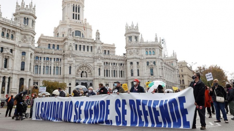 Participantes tras una pancarta en la manifestación de la Marea blanca en defensa de la sanidad pública que tiene lugar este domingo en Madrid, entre Neptuno y la plaza de Colón.