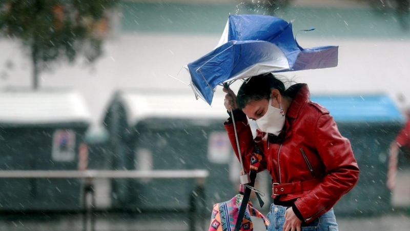 Una persona trata de protegerse de la intensa lluvia.