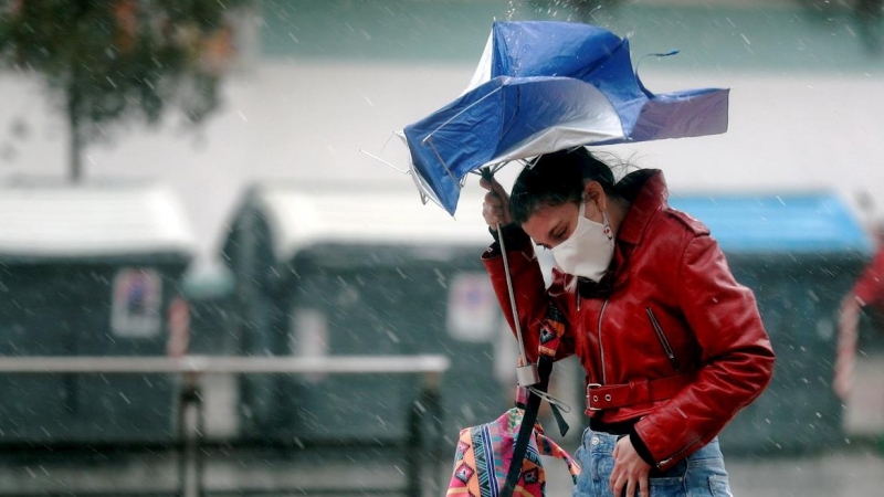 Una persona trata de protegerse de la intensa lluvia.