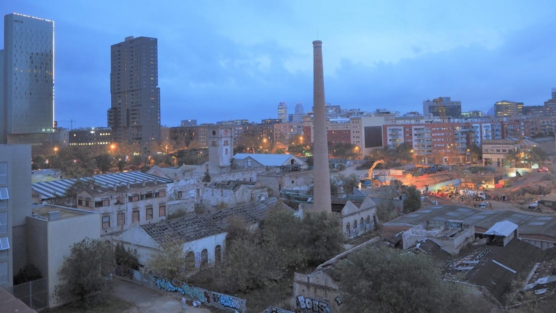 Las naves deterioradas de Can Ricart con su gran chimenea en pie, mientras a su alrededor se construyen oficinas y hoteles.