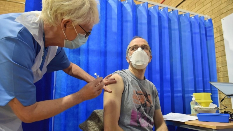 08/12/2020.- David Farrell, paciente de 51 años, recibe una de las dos vacunas de Pfizer y BioNtech en un centro de vacunación en Cardiff (Reino Unido).