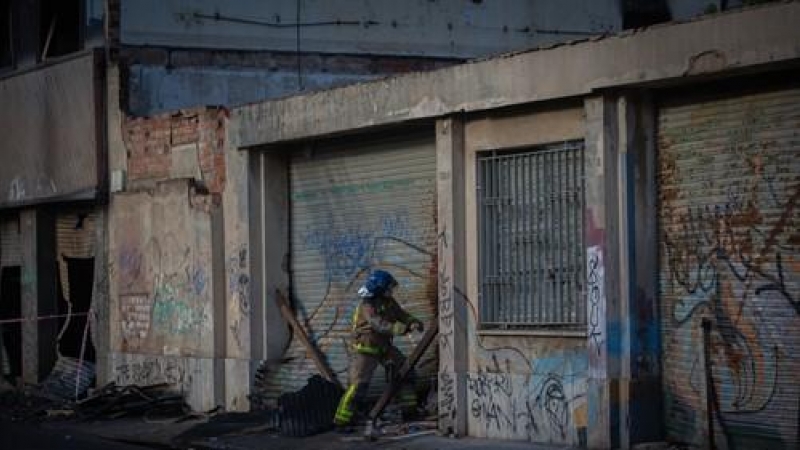 Bomberos retiran el cadáver de una de las personas fallecidas en el incendio de ayer en la nave okupada del barrio de Gorg, en Badalona, Barcelona, Catalunya