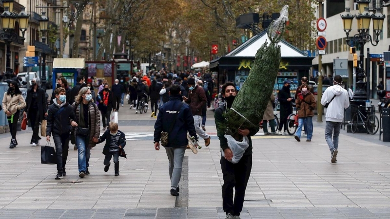 Una persona transporta un árbol de navidad por las Ramblas de Barcelona.