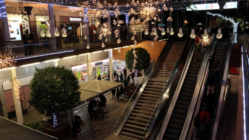 Compradors baixant per les escales mecàniques en una zona comercial del centre de Reus en el primer dissabte de la campanya de Nadal.