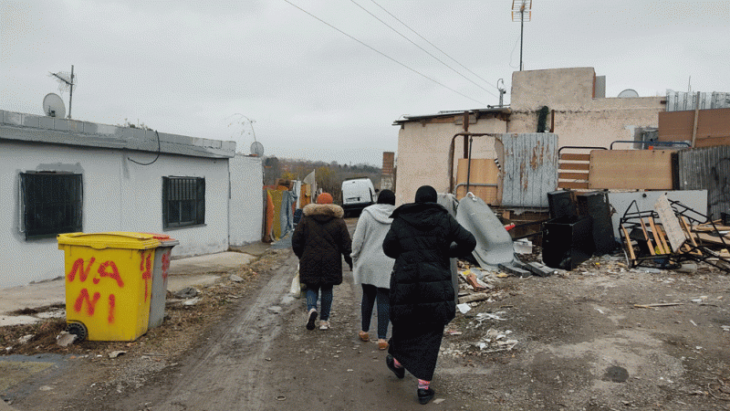 Las tres mujeres caminan hacia sus casas en una calle sin asfaltar y repleta de charcos y barro.