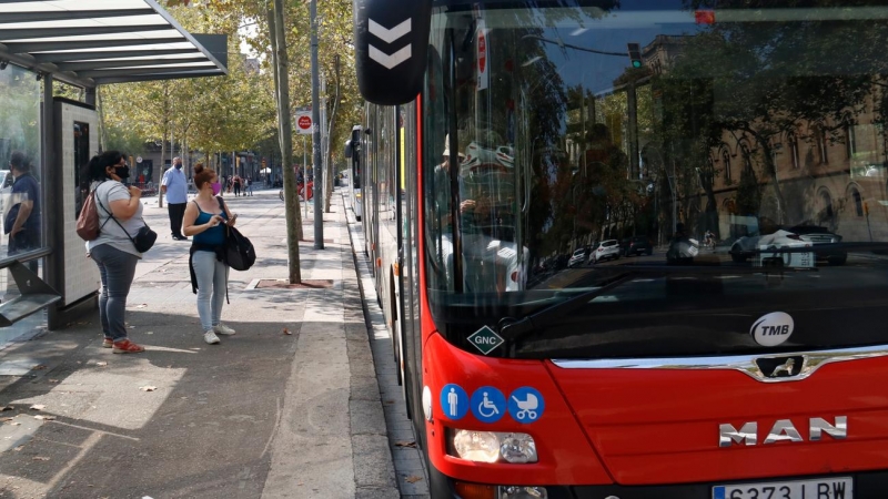 Un bus aturat a la plaça Universitat amb usuaris a la parada.