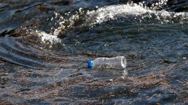 Una botella de plástico flota sobre las olas del mar.