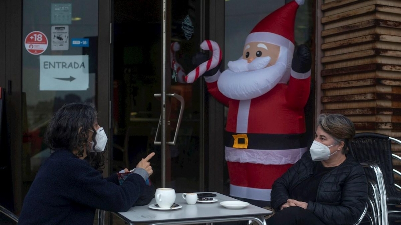 23/12/2020.- Dos personas conversan con la mascarilla puesta mientras se toman algo en la terraza de un bar en la víspera de Nochebuena, en Ourense.