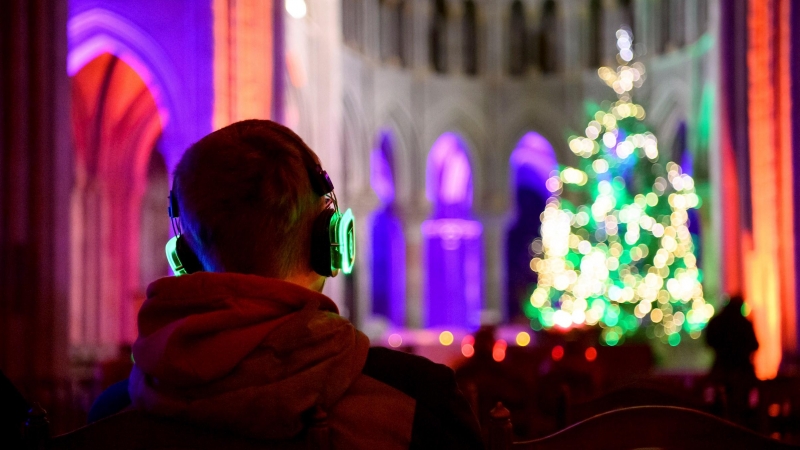 Una persona con mascarilla escucha con auriculares de discoteca silenciosos en la víspera de Navidad durante el evento 'La noche silenciosa, Navidad en los oídos' durante el brote de la enfermedad por coronavirus (COVID-19), en la Catedral de Lausana, Sui