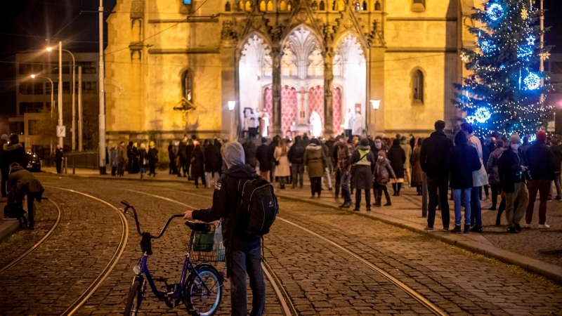 La gente escucha una misa de Nochebuena celebrada al aire libre frente a una iglesia en Praga, República Checa, el 25 de diciembre de 2020. El gobierno permitió la participación en la misa de medianoche, pero las iglesias solo se llenaron parcialmente. El