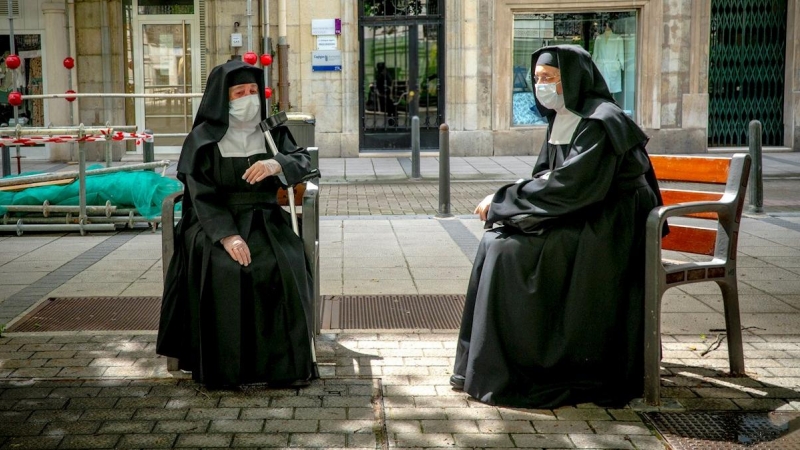 Dos monjas descansan en bancos manteniendo la distancia de seguridadhoy en el centro de Santander.