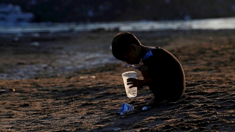 Un niño hondureño se cepilla los dientes este martes, en la orilla del río Suchíate tras que la Guardia Nacional de México impidiera a migrantes cruzar, en Tecún Umán (Guatemala). Cientos de migrantes cruzaron ayer el río Suchiate, que separa Guatemala de