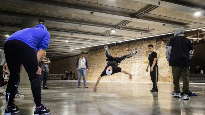 Un grupo de jóvenes hace 'break dance' al lado de la muralla de Barcelona.