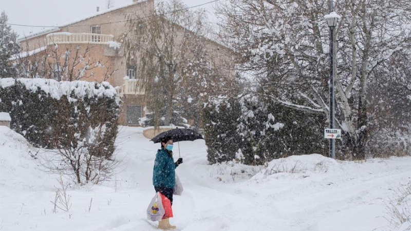 07/01/2021. Una mujer camina en medio de una intensa nevada con una bolsa de compra este jueves en la pedanía de Campo de San Juan, Moratalla. - EFE