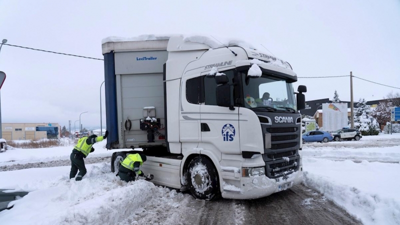 Miembros de la Guardia Civil y Protección Civil ayudan a desatascar los camiones embolsados en el polígono La Paz de Teruel.