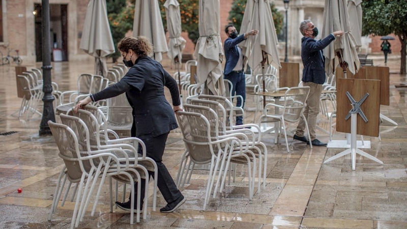 Unos trabajadores de un restaurante del centro de Valencia recogen la terraza. EFE/Biel Aliño