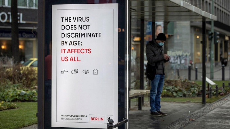 Un cartel advierte del riesgo de contagio de la covid-19 para cualquier edad, en una parada de autobús en Berlin.