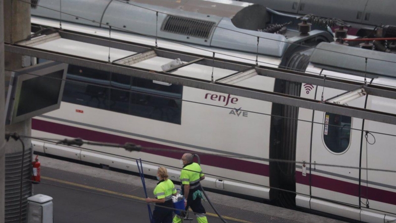 Dos trabajadores pasan junto a un tren AVE de Renfe en un andén en la estación de Atocha, en Madrid. E.P./Marta Fernández Jara