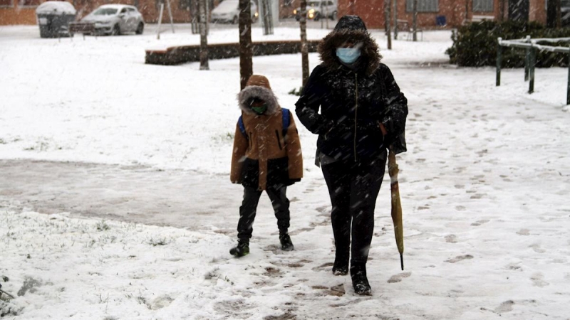 Una mujer y un niño caminan por una calle nevada en Ciudad Real.